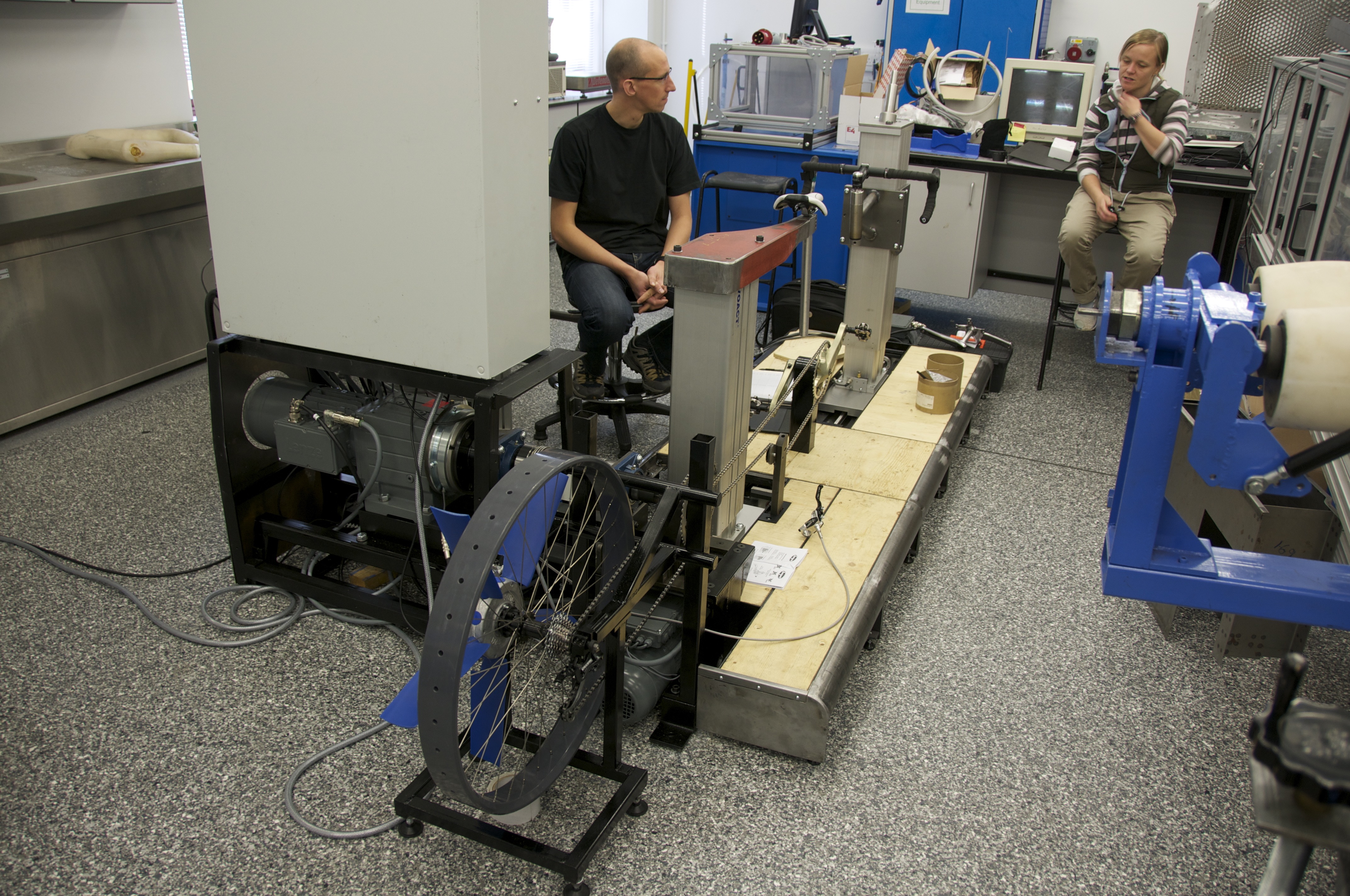 two researchers discussing the ergometer in the testing facility